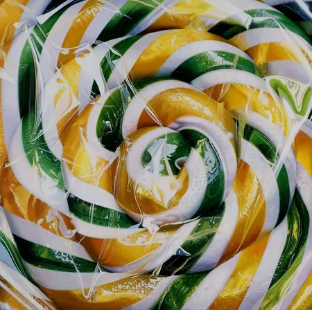 Hyperrealistische Malerei: spiralförmiges Bonbon in transparenter Folie, Goldgelb, Tiefgrün und Cremeweiss